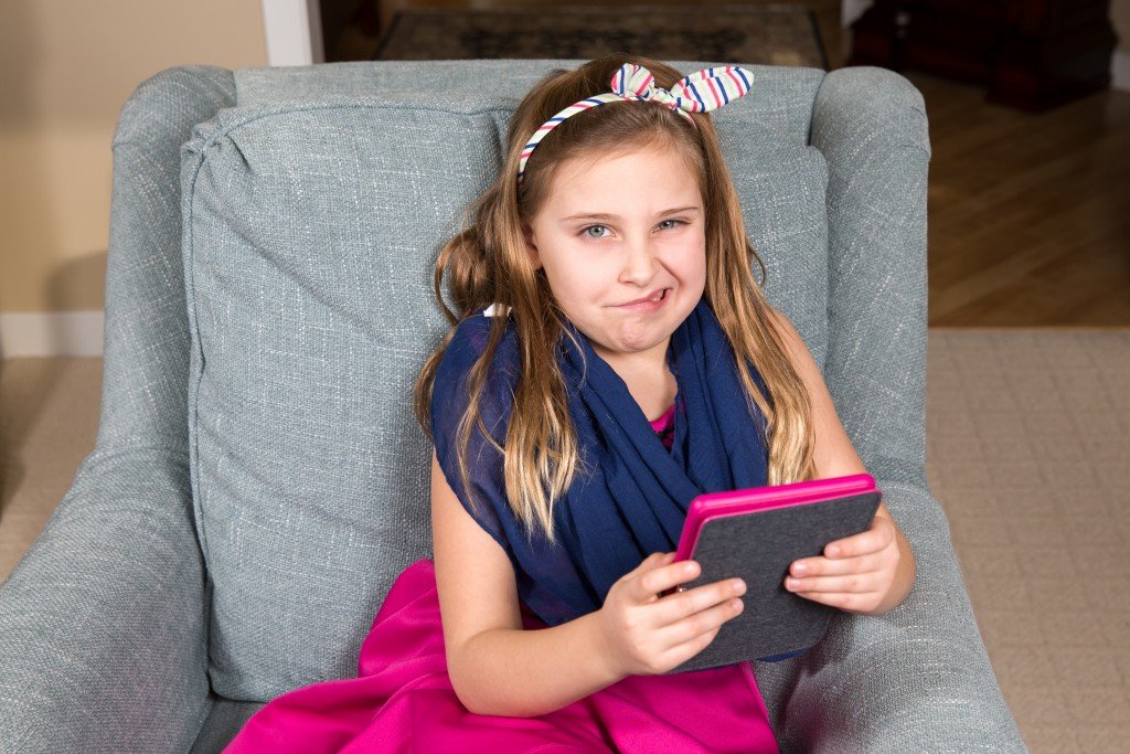 Grimacing Girl in a Chair with a Tablet